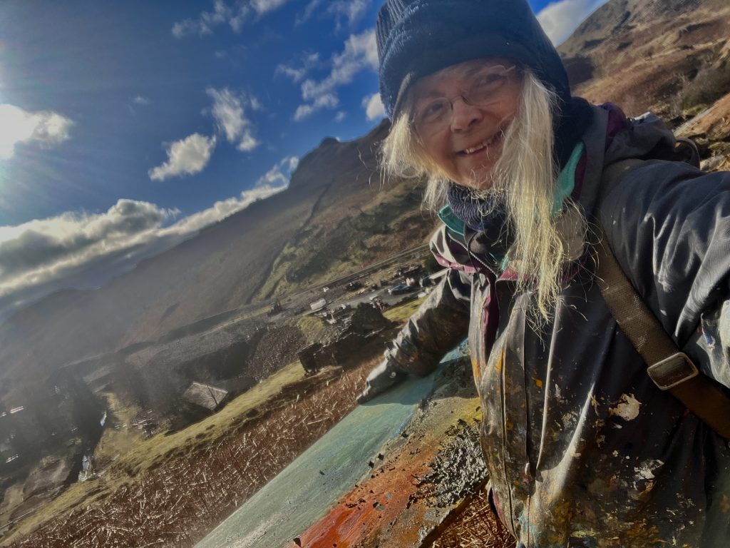 Frances Hatch out on a hillside above the coast, working bag over her shoulder.